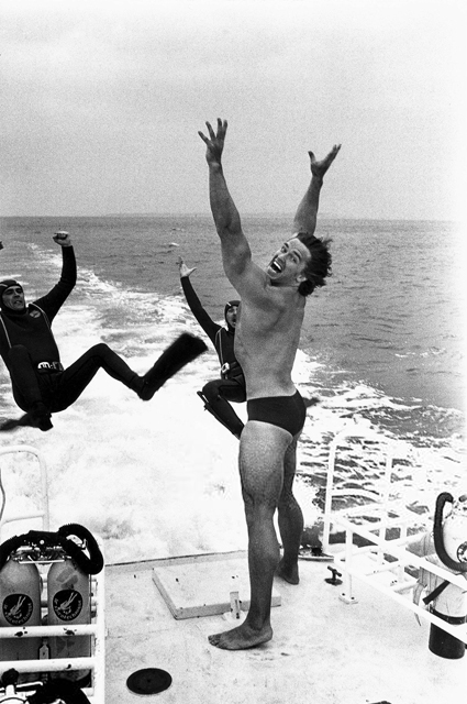 Арнольд Шварценеггер "сбрасывает" двух дайверов в воду, рекламируя фильм "Качая железо" (Pumping Iron) со своим участием, 1977 год